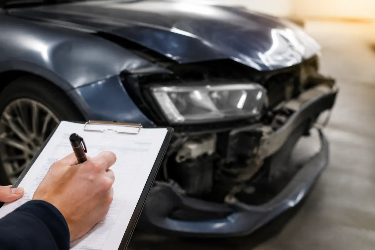 Gros plan sur le rapport rédigé par un expert automobile posé sur un capot plissé