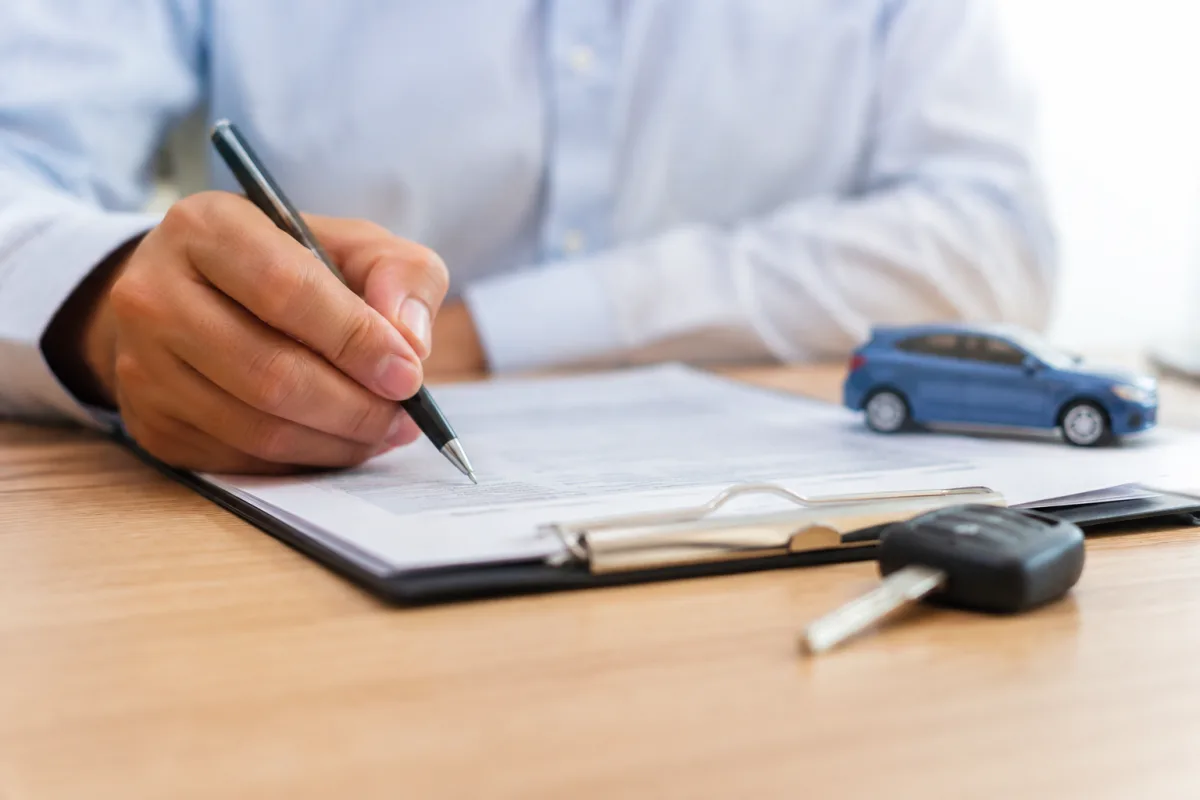 Tout comprendre sur le délai de rétractation d'une assurance auto Gros plan sur un stylo signant la case d'un formulaire de renonciation d'assurance voiture